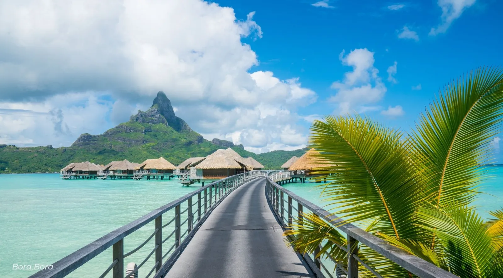 Wooden pier leading to overwater bungalows with Mount Otemanu in the distance