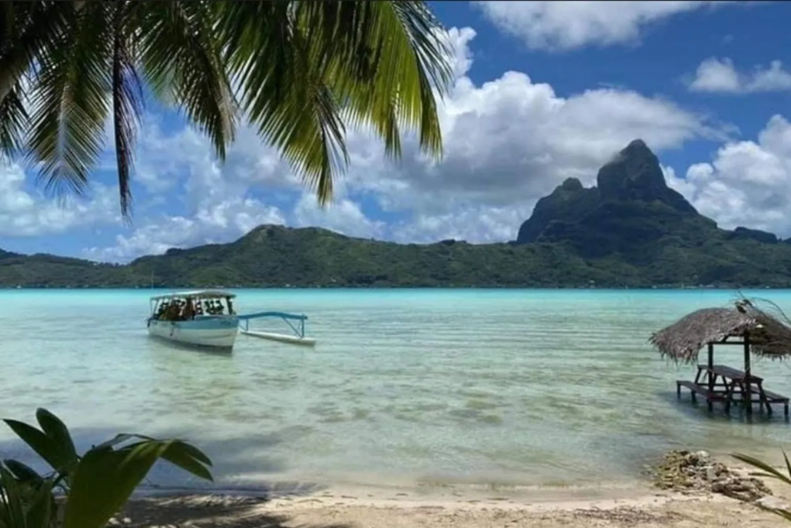 Boat off a motu beach with the main island behind