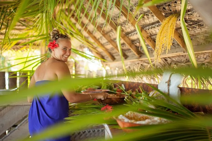 Host serving lunch under a palm-thatched shelter on a motu