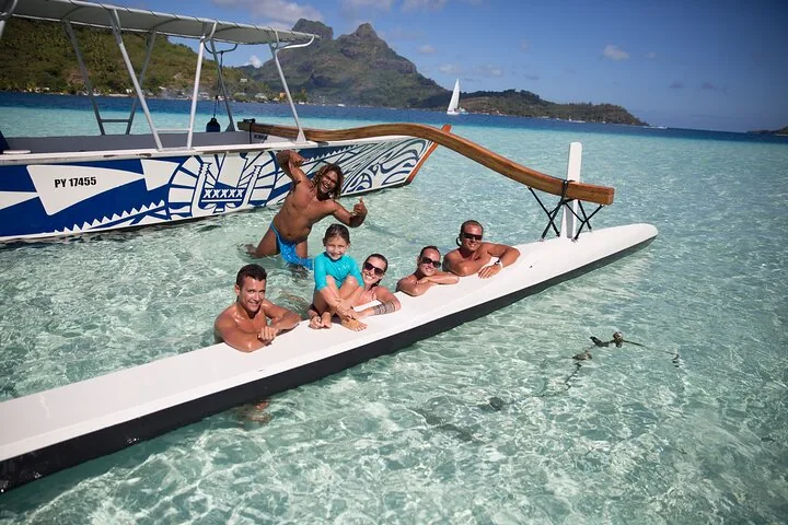 Guests relaxing on the outrigger hull of the boat in shallow water