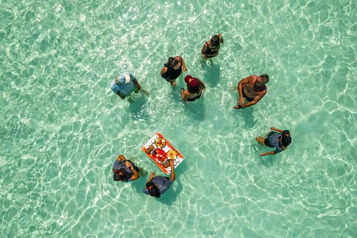 Guests gathered around the floating bar in shallow water