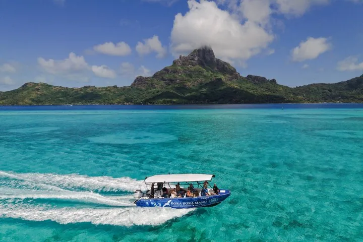 Manu boat speeding across the lagoon below Mount Otemanu