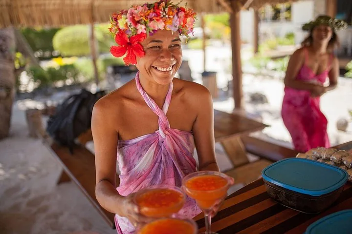 Host in a flower crown serving drinks on the motu
